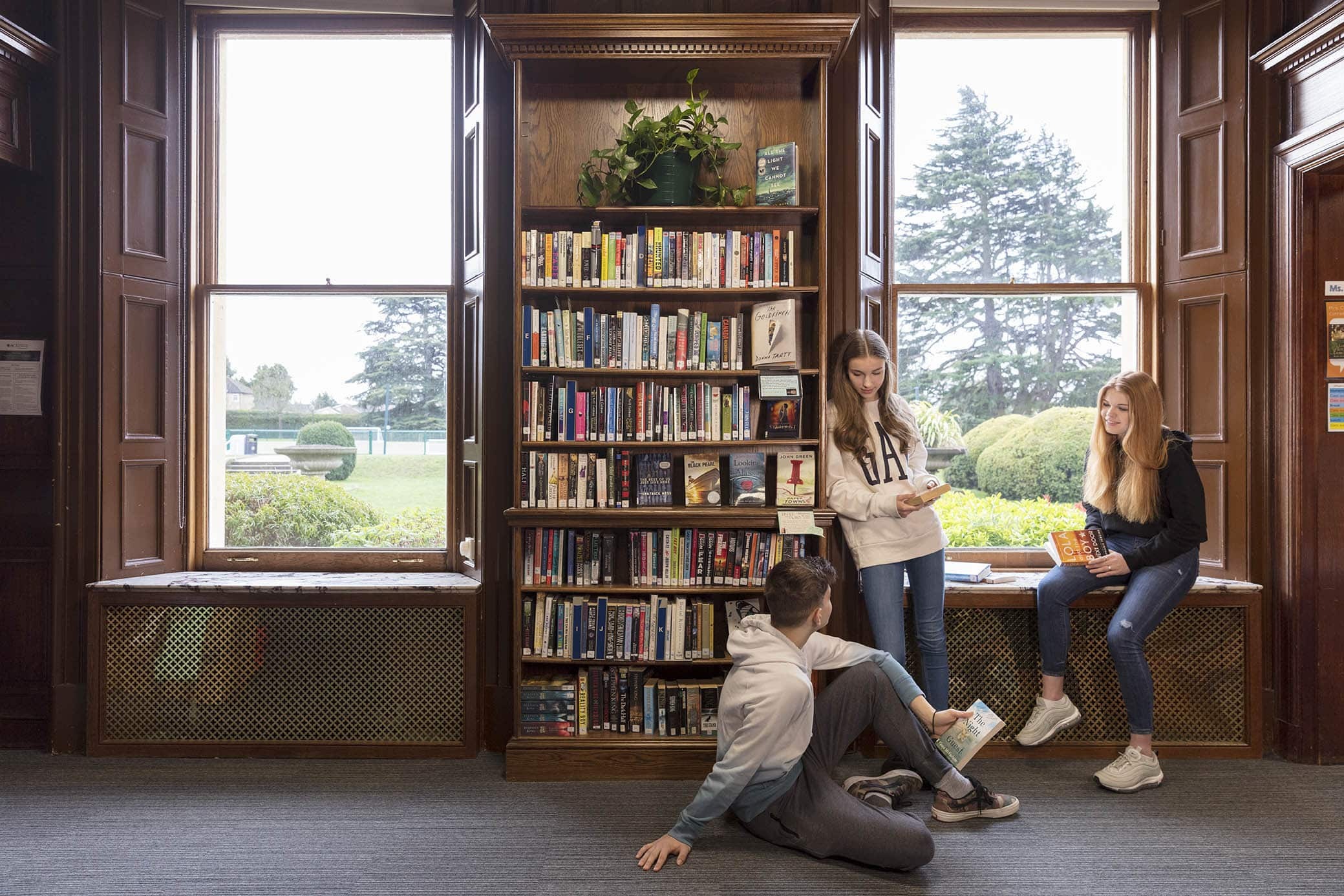 Upper School pupils reading in the wood-panelled library at ACS Hillingdon